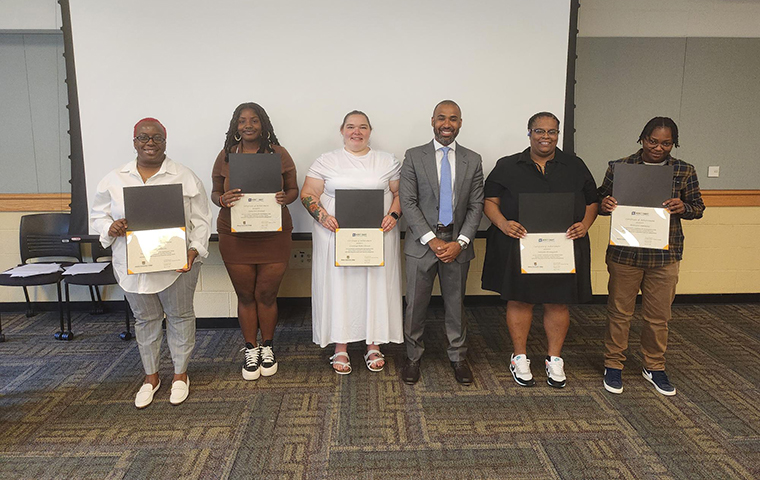 Monroe Community College students holding MSFCP completion certificates