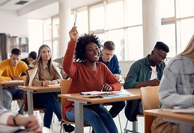 Colleges students in a classroom; African American student with her hand raised