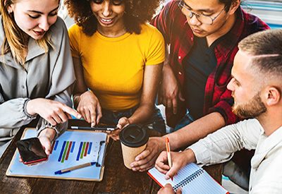 Multi ethnic coworkers using tablet device on creative office - College students with laptop while sitting at table - Group of young people study for school assignment - Youth, tech, start up concept